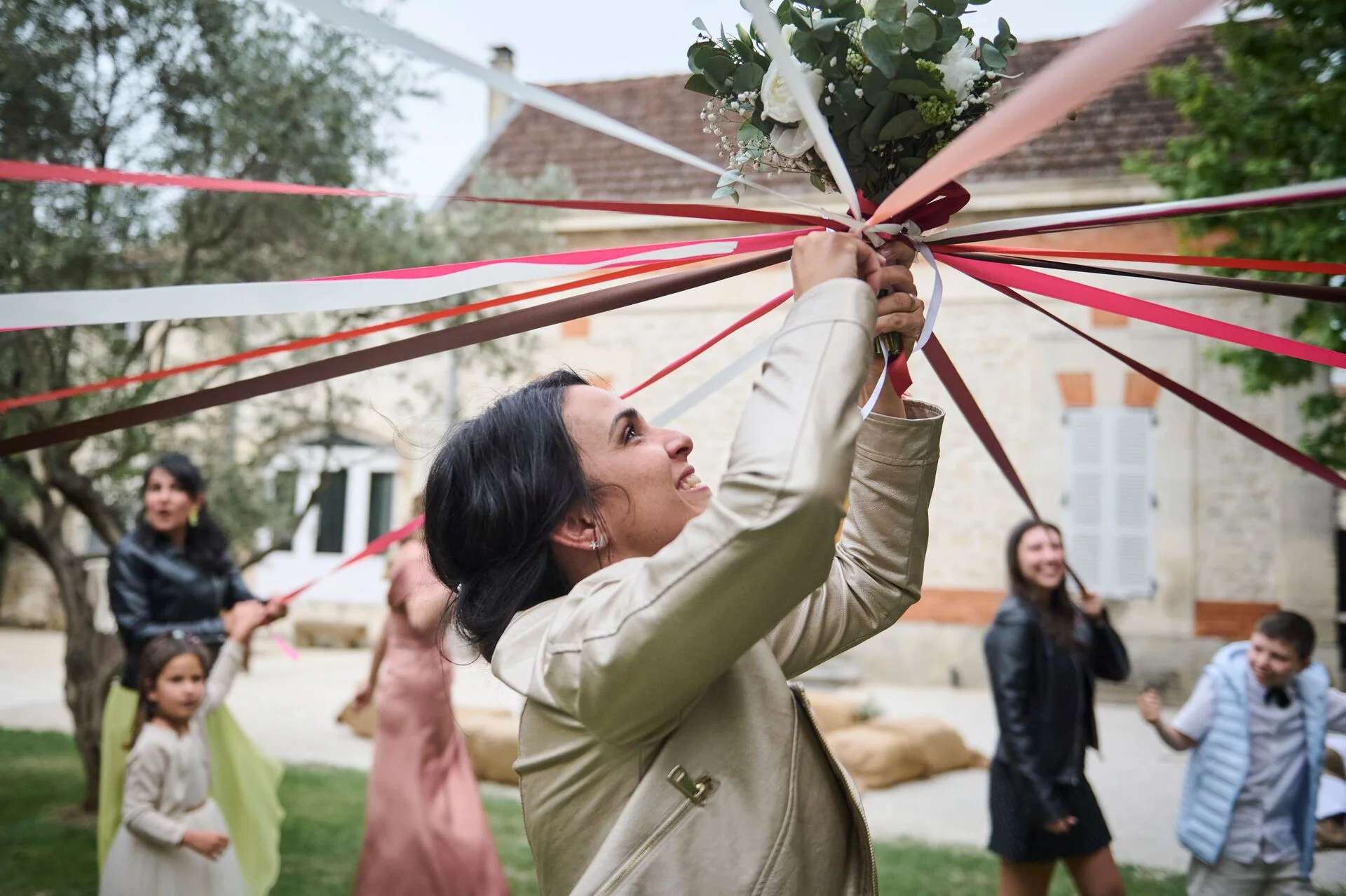 Mariée tenant son bouquet à la main avec des participantes au jeu du bouquet de la mariée