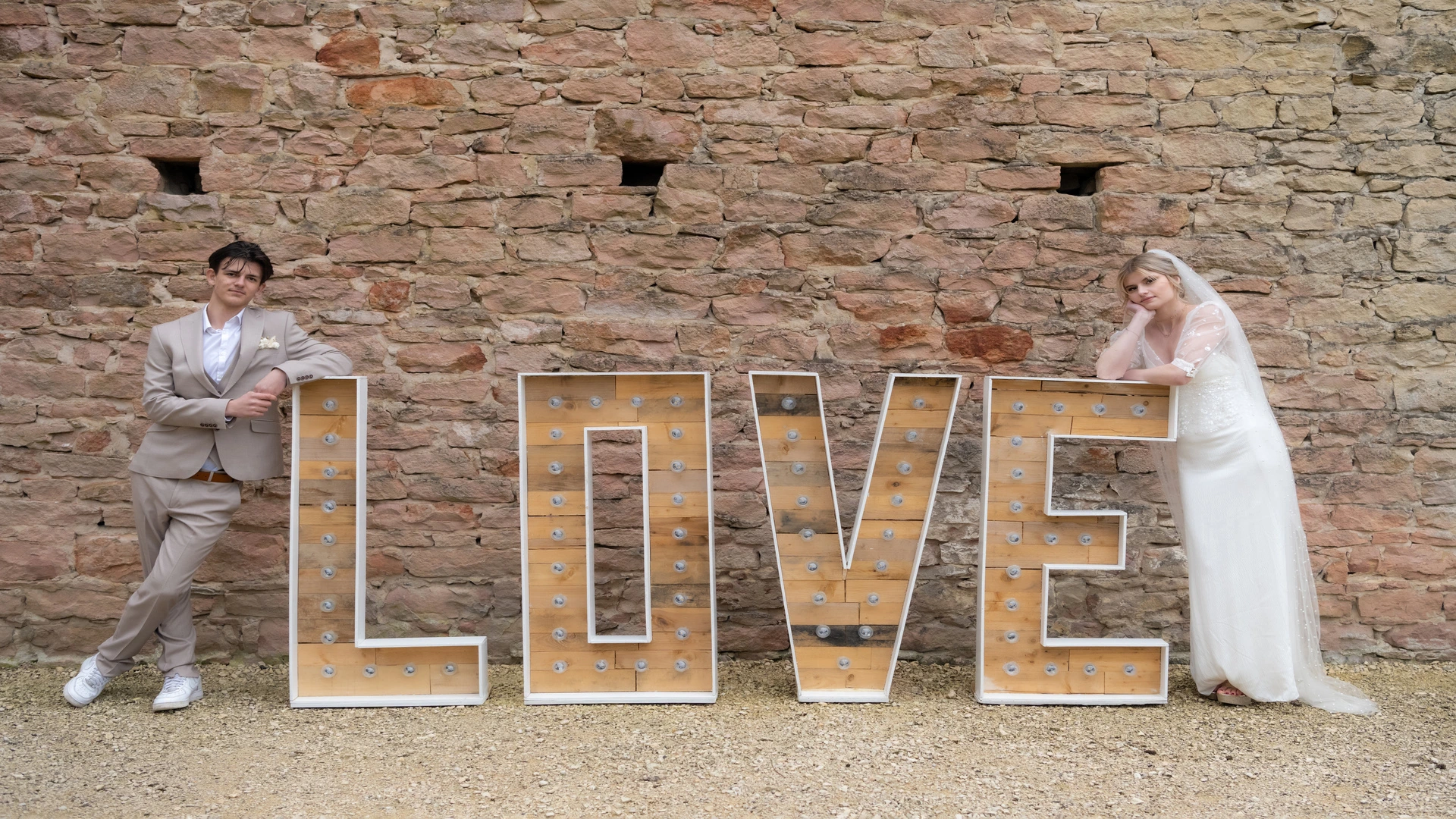 Lettres géantes LOVE en bois avec un couple qui pose autour pour leur mariage