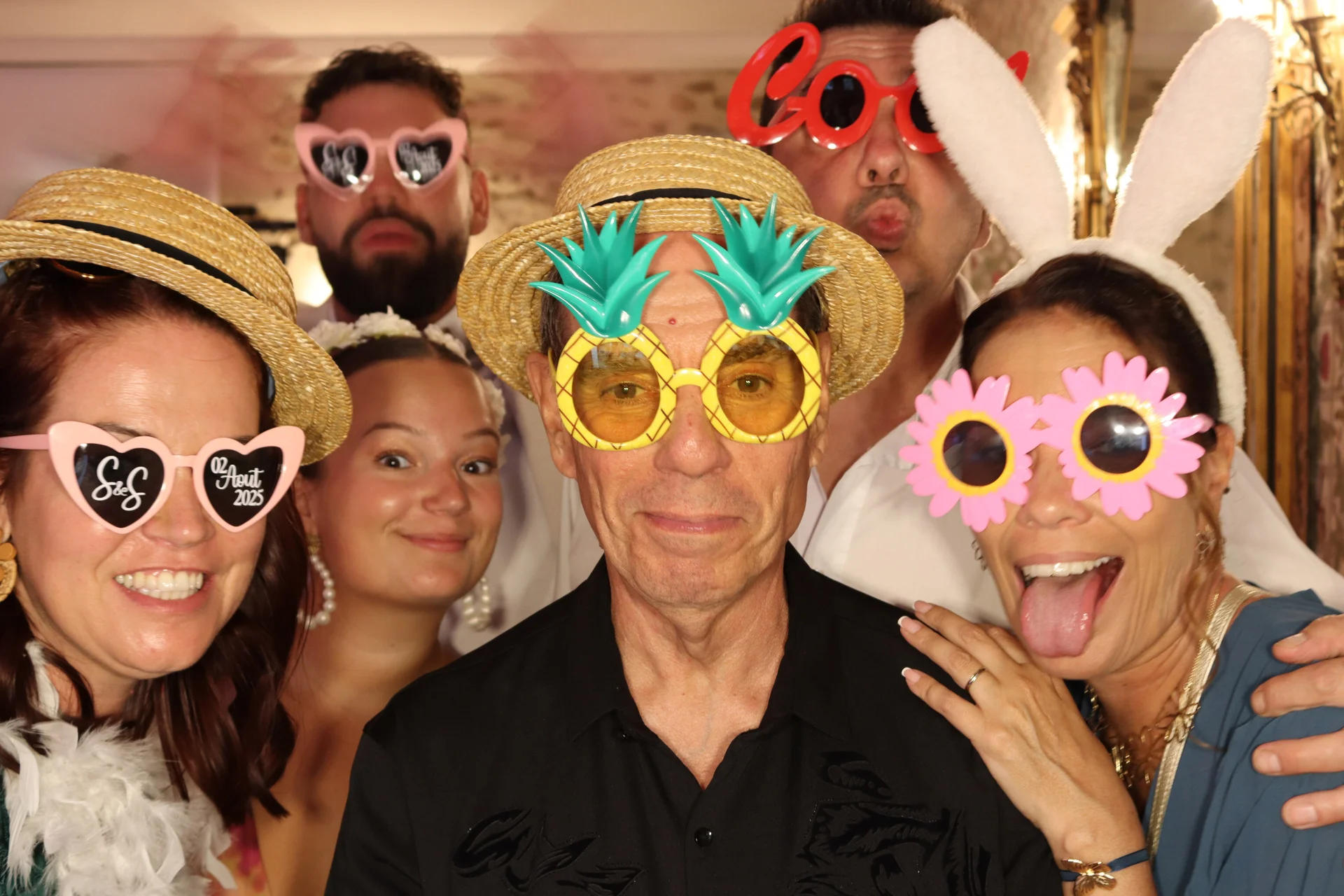 Famille joyeuse qui pose devant le photobooth avec des accessoires pour un mariage